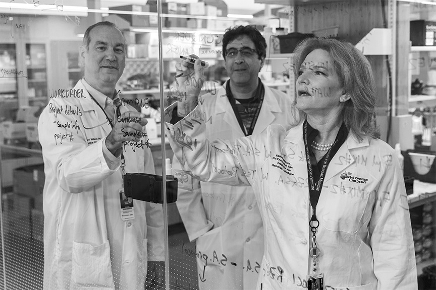Researchers in the Steve and Cindy Rasmussen Institute for Genomic Medicine problem solving on a dry erase board