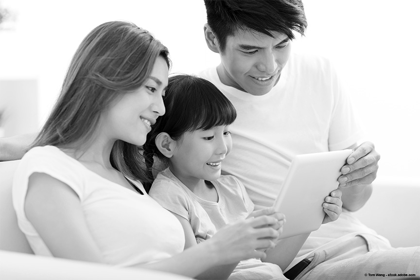 mother and father looking at a book with their daughter