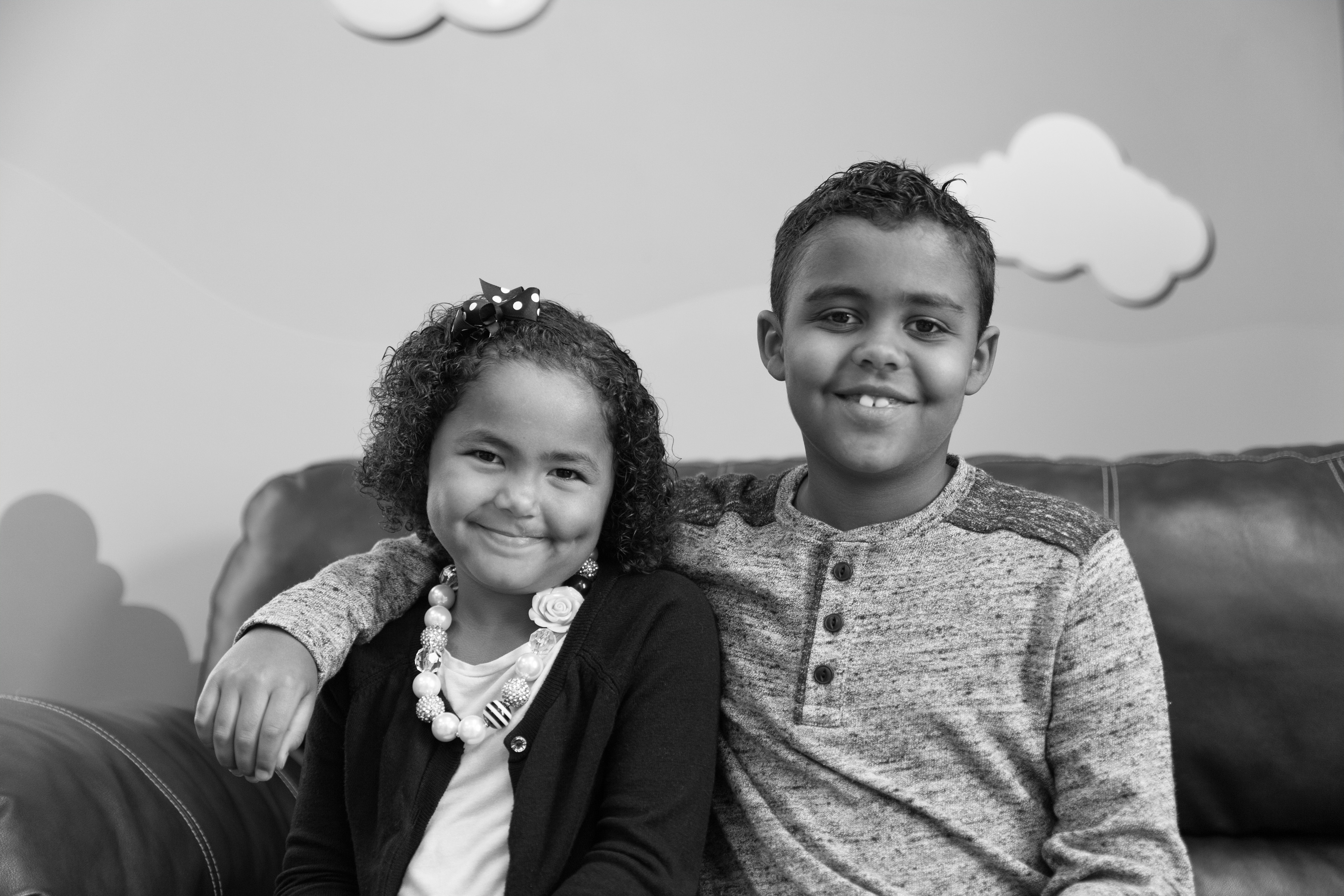 Little sister and big brother sitting on a couch