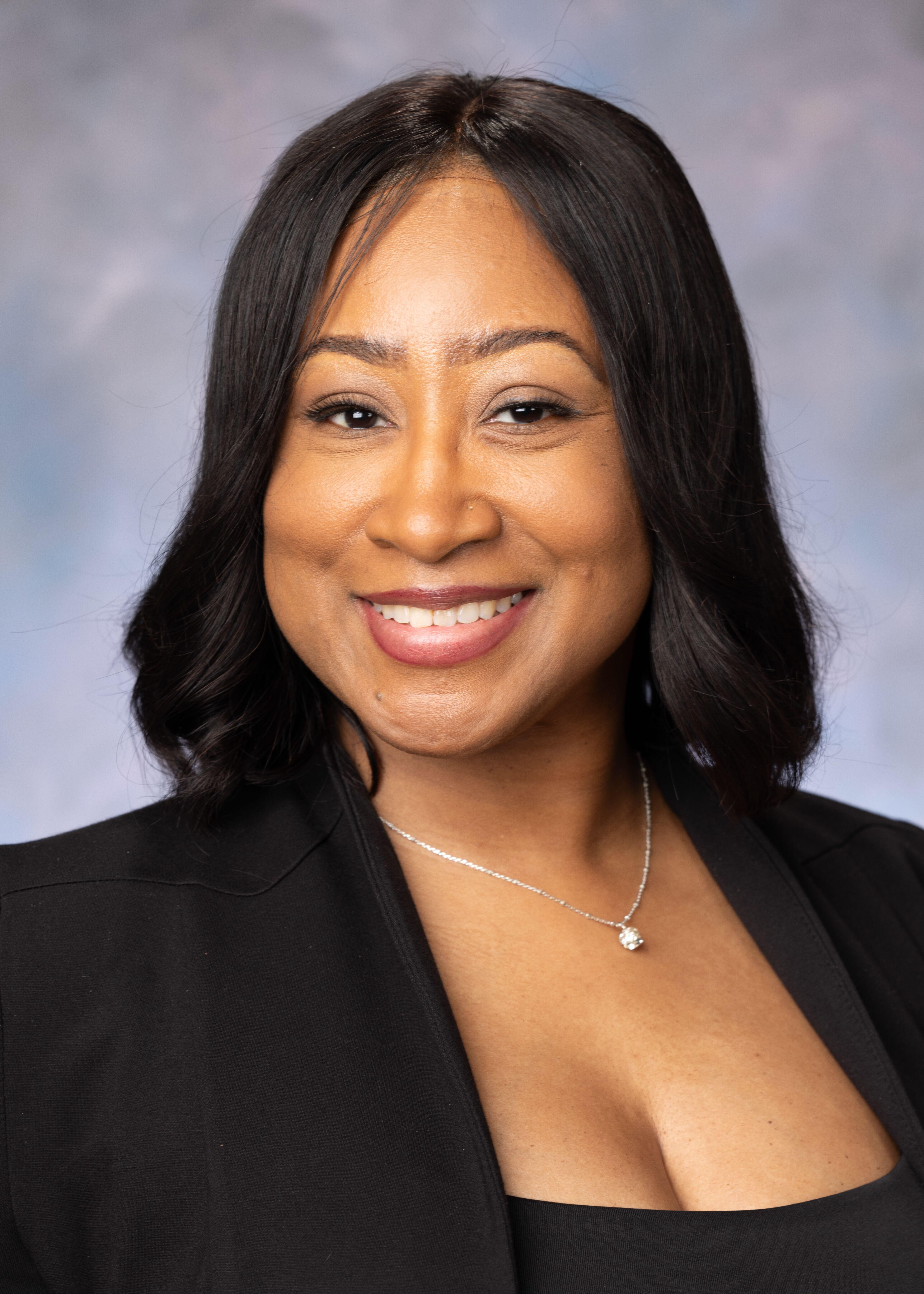 Portrait of Jamee Shelley. She has shoulder length black hair and is wearing a black top with a small silver necklace.