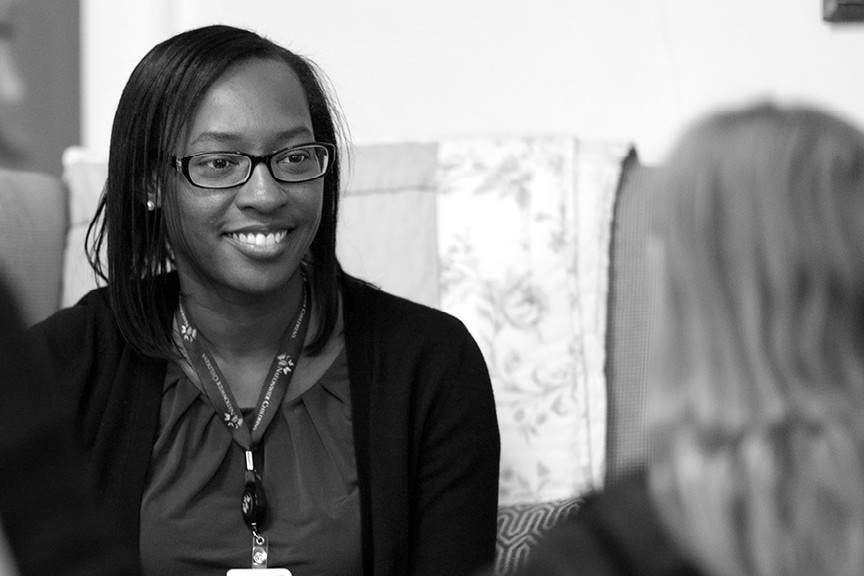 A behavioral health employee is smiling and addressing a teenager.